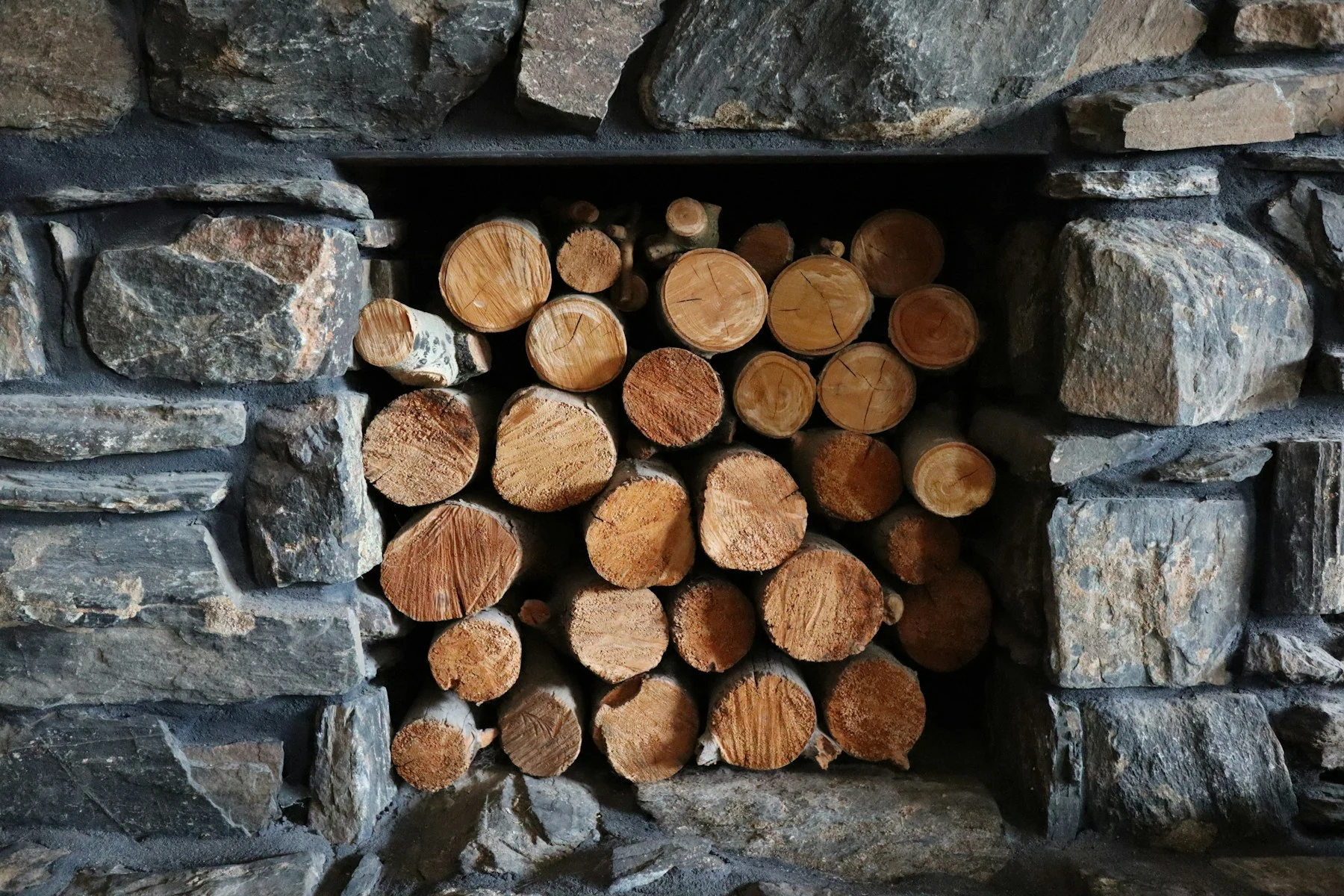 Split firewood stacked neatly inside a stone hearth